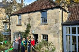 People standing outside a period home on a sunny day