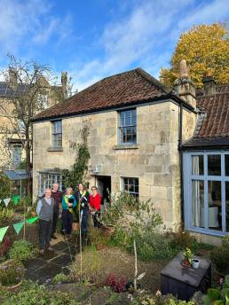 People standing outside a period home on a sunny day